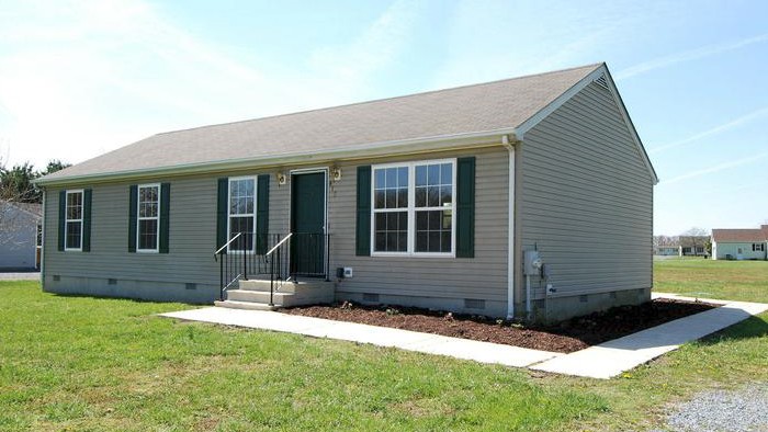 tan house with green grass and blue sky