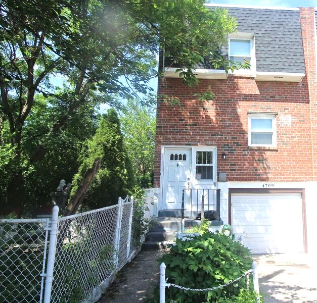 Fenced in home with red brick and white garage door