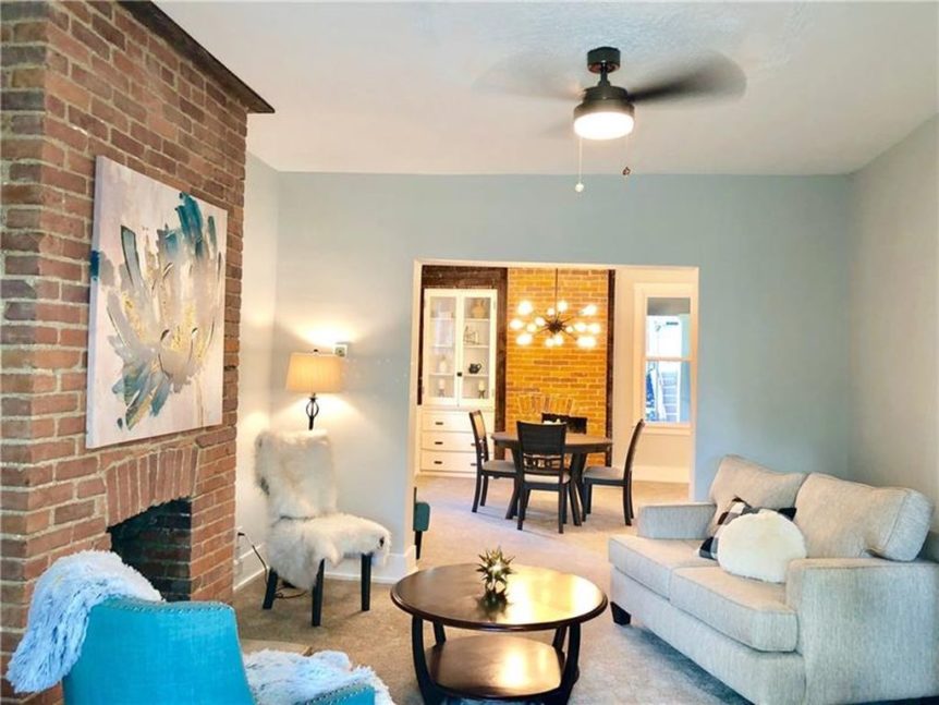 Renovated living space with light blue walls and a brick fireplace accent