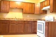 Renovated kitchen with yellow lighting, wooden cabinets, white stove/oven
